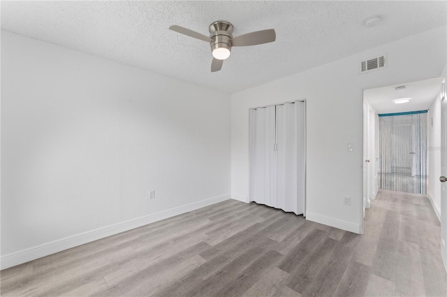 unfurnished bedroom with a textured ceiling, light wood-type flooring, and ceiling fan