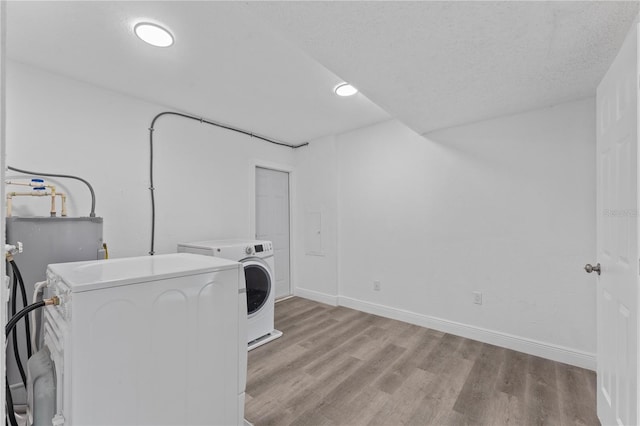 laundry area with light hardwood / wood-style flooring, washer and dryer, and a textured ceiling