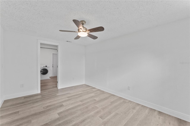 unfurnished room featuring washer / dryer, light hardwood / wood-style floors, and a textured ceiling