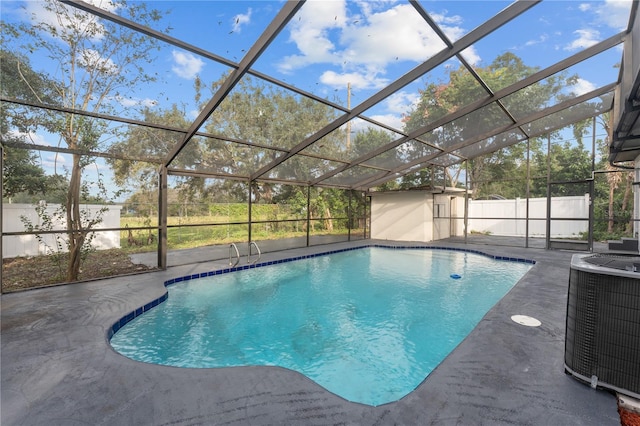 view of swimming pool with a patio, cooling unit, a storage unit, and glass enclosure