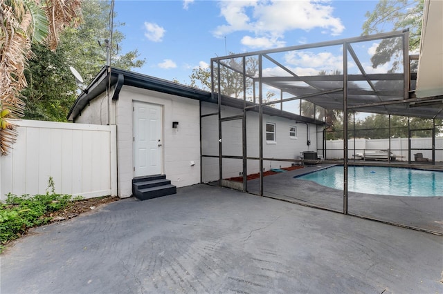 view of pool with central air condition unit, a patio area, and glass enclosure