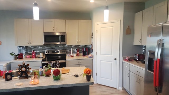 kitchen featuring appliances with stainless steel finishes, decorative backsplash, light wood-type flooring, and pendant lighting