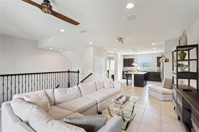 tiled living room featuring ceiling fan and a textured ceiling