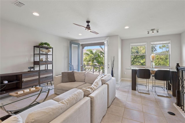 living room featuring ceiling fan, a textured ceiling, light tile patterned floors, and a wealth of natural light