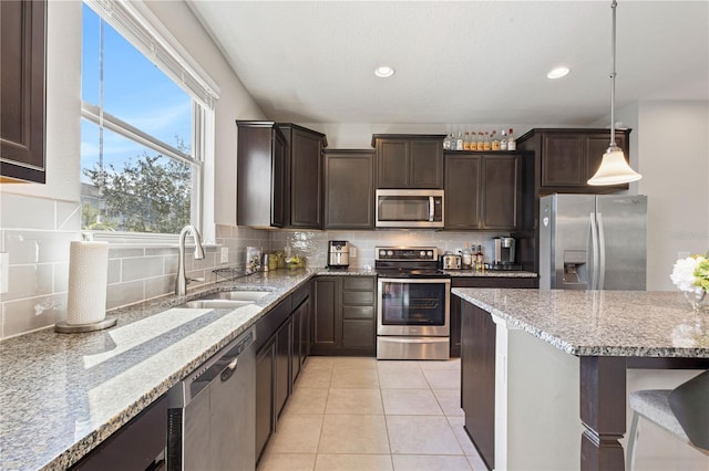 594 Piazza Pt, Oviedo, FL 32765 - kitchen with stainless steel appliances, a sink, dark brown cabinetry, decorative backsplash, and light stone counters