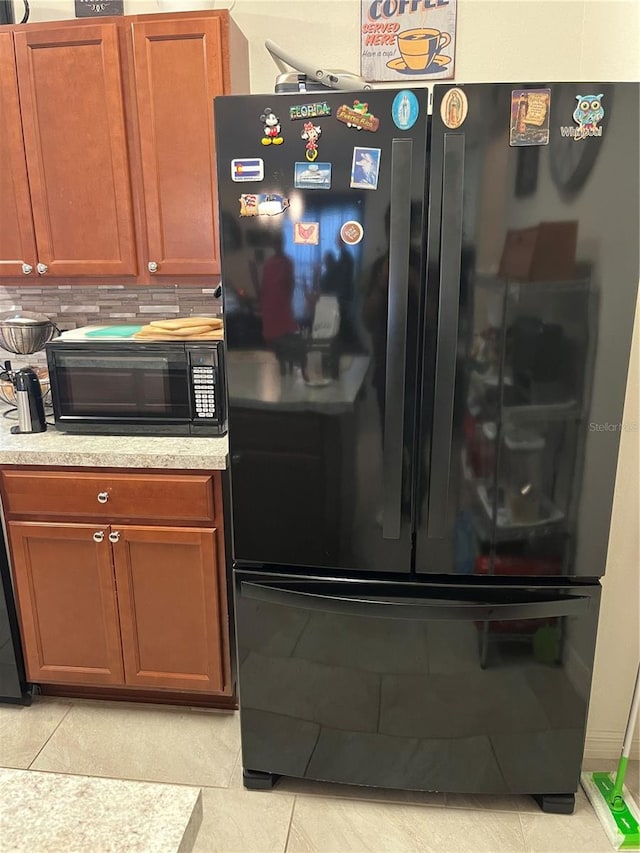 kitchen with tasteful backsplash, black appliances, and light tile patterned floors