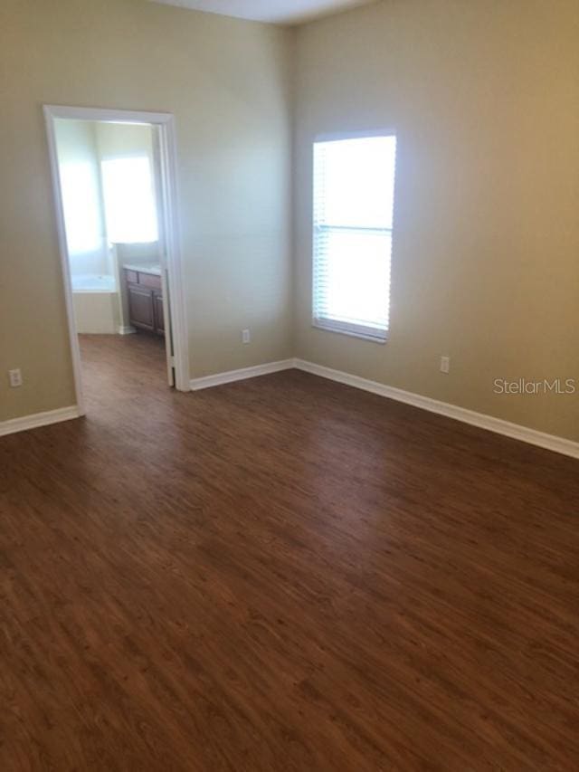 spare room with a wealth of natural light and dark wood-type flooring