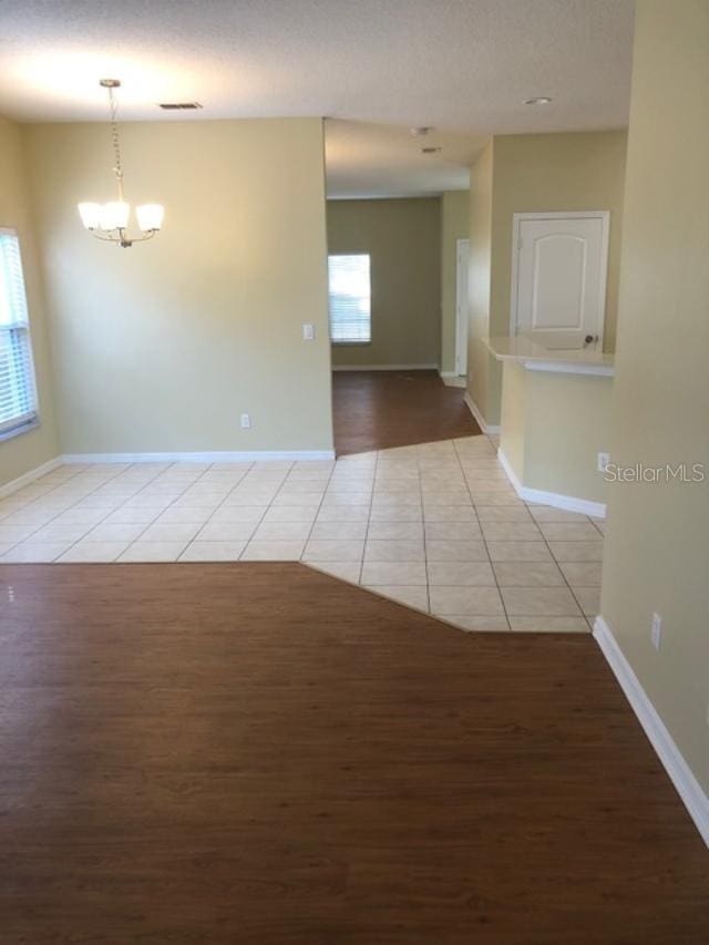 spare room featuring an inviting chandelier and light tile patterned floors