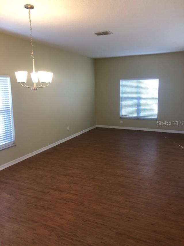 unfurnished room with dark hardwood / wood-style floors and an inviting chandelier