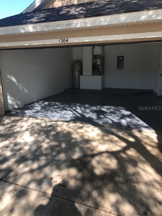 garage with water heater, electric panel, and heating unit