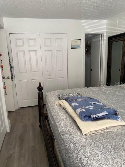 bedroom featuring a textured ceiling, a closet, and dark hardwood / wood-style flooring