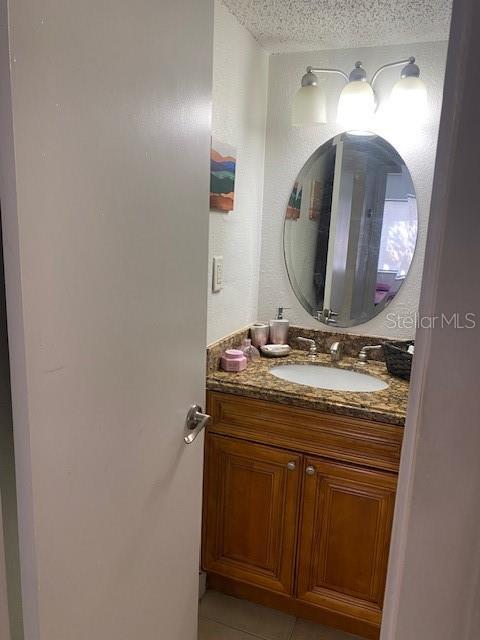bathroom with tile patterned flooring, vanity, and a textured ceiling