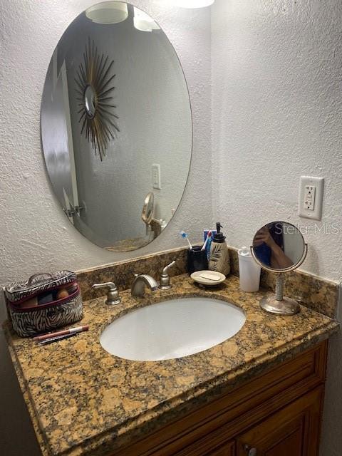 bathroom featuring a textured wall and vanity