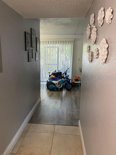 hallway featuring light tile patterned floors and a textured ceiling