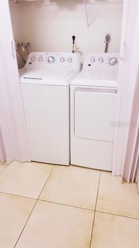 clothes washing area with washer and clothes dryer and tile patterned floors