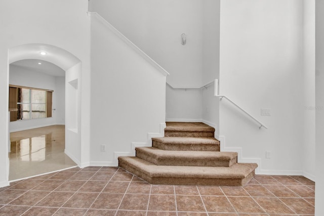 stairs with a towering ceiling and tile patterned floors