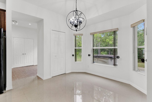 spare room with a chandelier and light tile patterned flooring