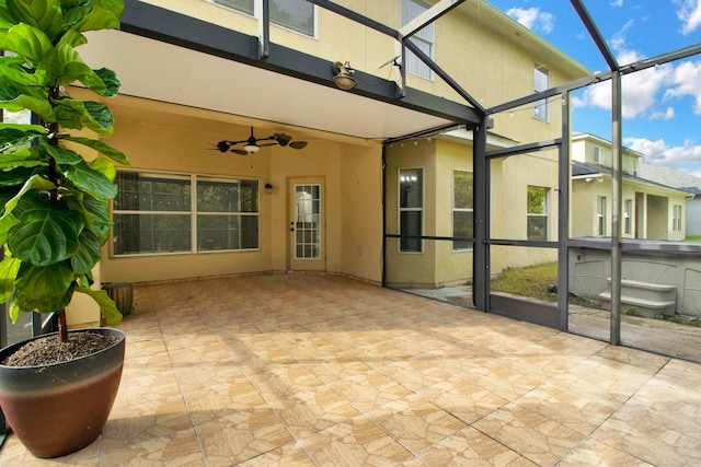 view of patio / terrace featuring a hot tub, glass enclosure, and ceiling fan