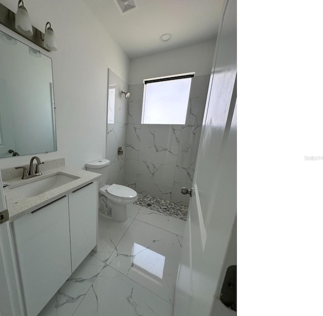 bathroom featuring marble finish floor, a marble finish shower, visible vents, toilet, and vanity