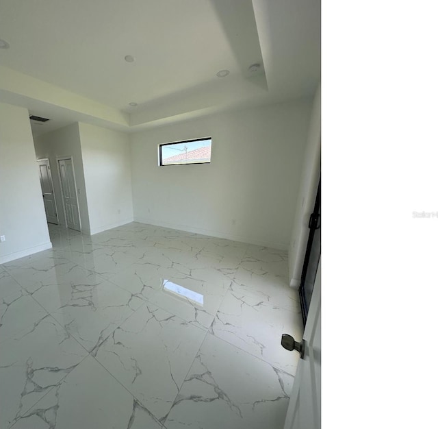 unfurnished room featuring marble finish floor, a tray ceiling, visible vents, and baseboards