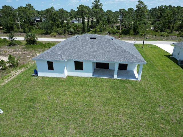 exterior space with a patio area, roof with shingles, a yard, and stucco siding