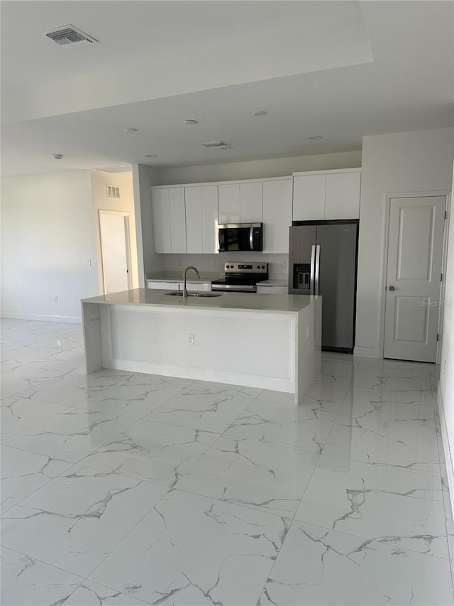 kitchen featuring visible vents, white cabinets, an island with sink, appliances with stainless steel finishes, and a sink