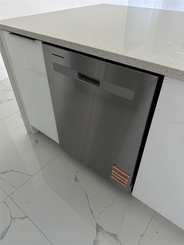 interior details featuring dishwasher, modern cabinets, white cabinetry, and light stone countertops