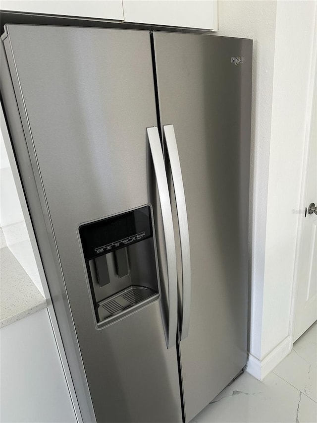 room details with light stone counters, white cabinets, and stainless steel refrigerator with ice dispenser