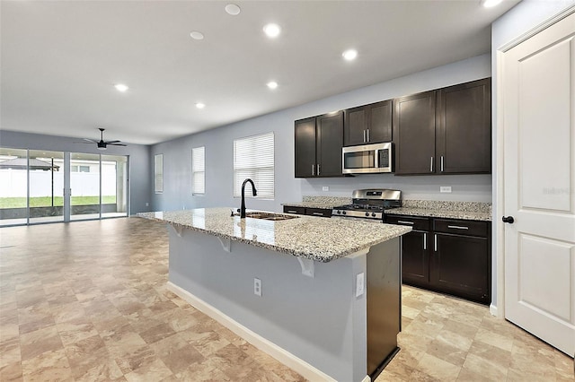 kitchen with ceiling fan, a breakfast bar area, a center island with sink, sink, and appliances with stainless steel finishes