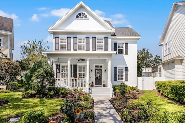 greek revival inspired property with covered porch, ceiling fan, and a front lawn