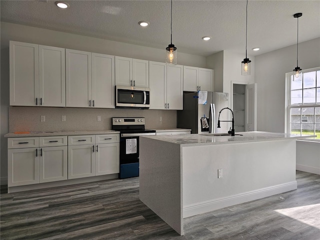 kitchen with an island with sink, hanging light fixtures, and stainless steel appliances