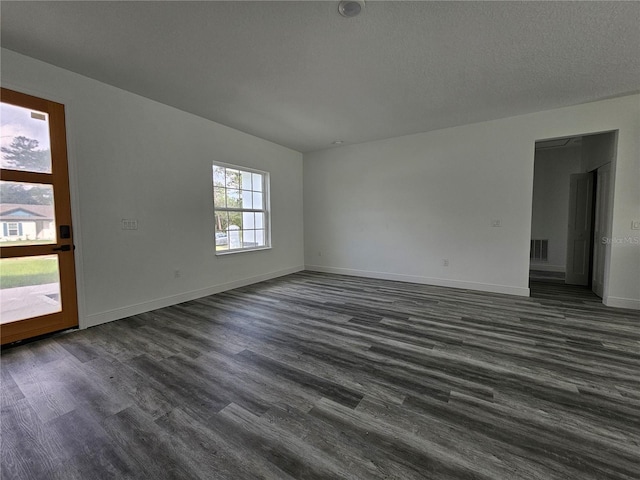 spare room with a textured ceiling and dark hardwood / wood-style flooring