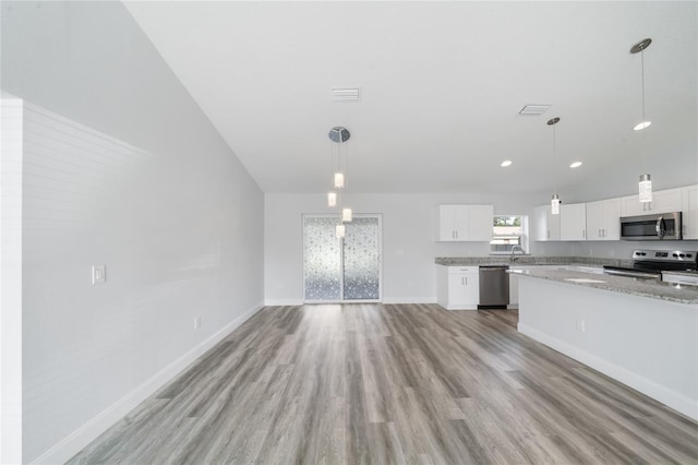 kitchen with white cabinets, hanging light fixtures, appliances with stainless steel finishes, light stone countertops, and light hardwood / wood-style floors