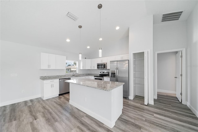 kitchen with hanging light fixtures, white cabinetry, high vaulted ceiling, stainless steel appliances, and a center island