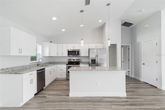 kitchen featuring white cabinets, stainless steel appliances, hanging light fixtures, and a kitchen island