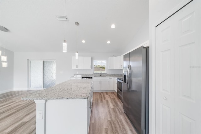 kitchen with white cabinets, hanging light fixtures, stainless steel appliances, light hardwood / wood-style floors, and a center island