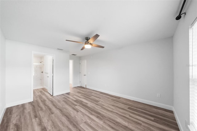 unfurnished bedroom with ensuite bathroom, light wood-type flooring, and ceiling fan