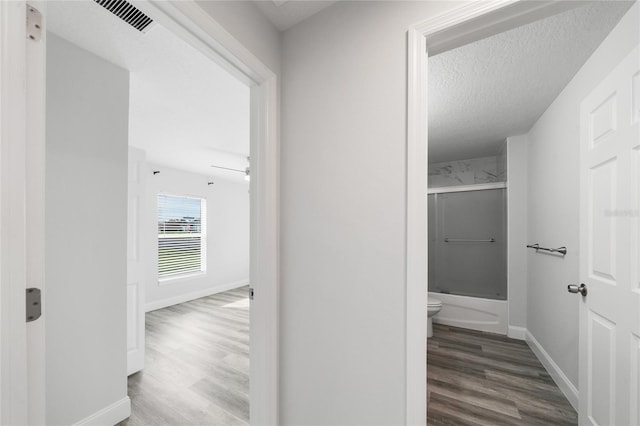 hall with a textured ceiling and hardwood / wood-style floors