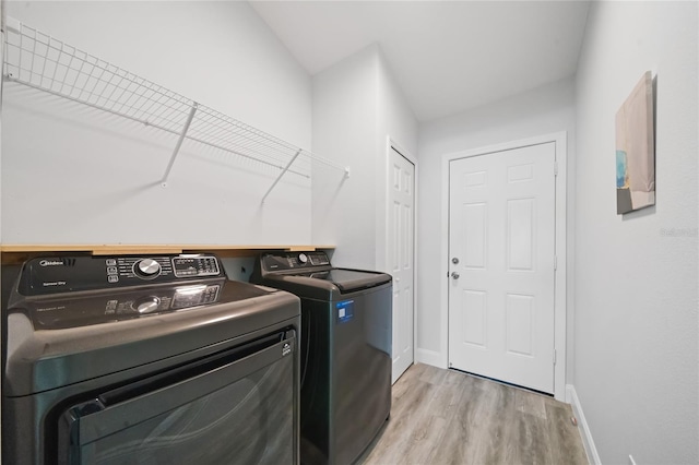 laundry area with light hardwood / wood-style floors and washer and clothes dryer