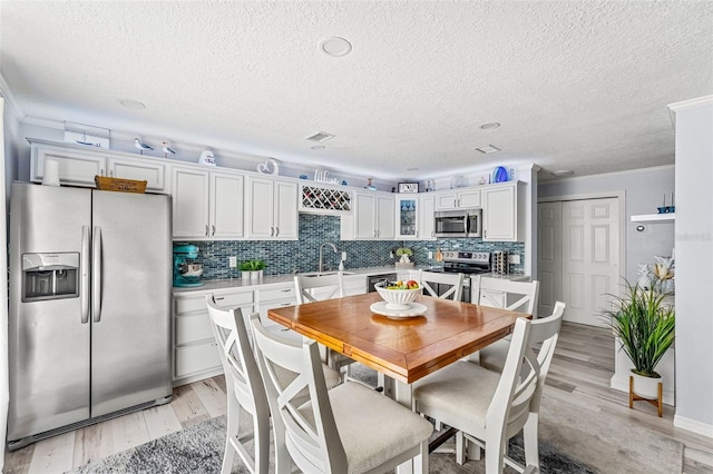 dining room with a textured ceiling, sink, and light wood-type flooring