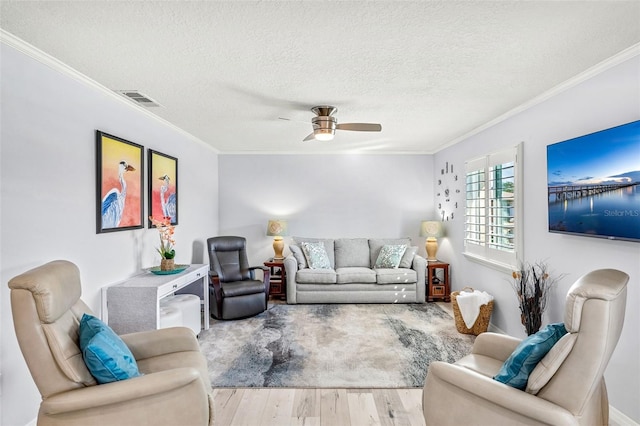 living room with ornamental molding, a textured ceiling, light hardwood / wood-style floors, and ceiling fan