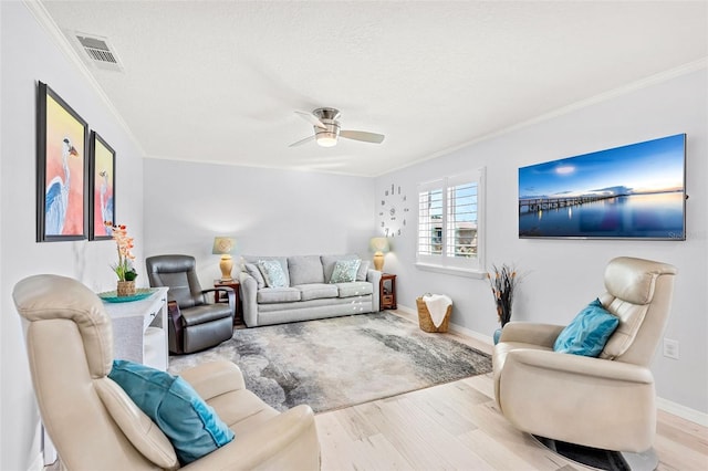 living room featuring light hardwood / wood-style floors, ornamental molding, a textured ceiling, and ceiling fan