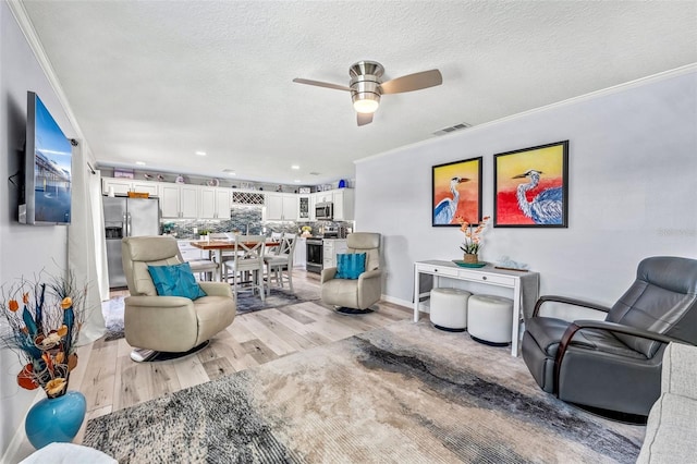 living room featuring crown molding, a textured ceiling, light hardwood / wood-style floors, and ceiling fan