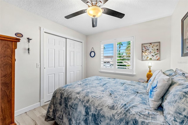 bedroom with light hardwood / wood-style floors, a textured ceiling, a closet, and ceiling fan