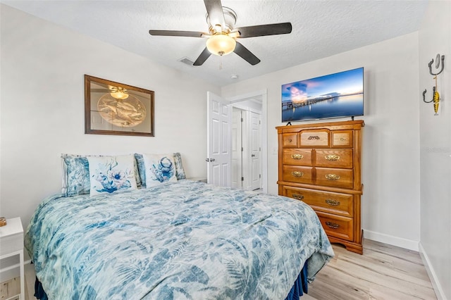 bedroom with light hardwood / wood-style flooring, a textured ceiling, and ceiling fan