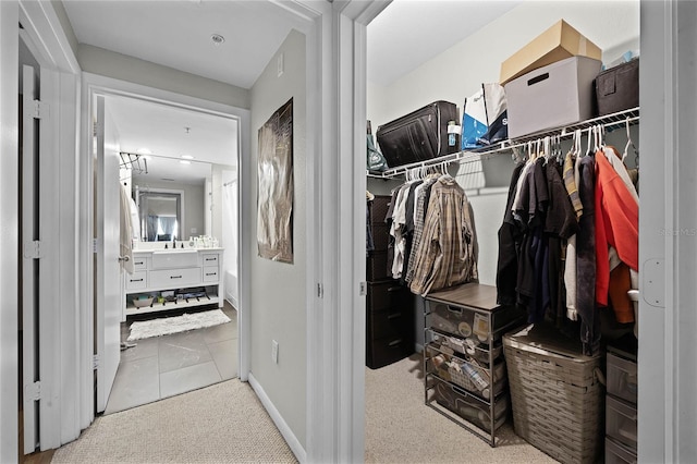 walk in closet featuring sink and light colored carpet