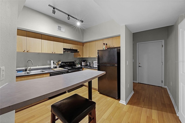 kitchen featuring sink, rail lighting, light brown cabinets, light hardwood / wood-style flooring, and black appliances