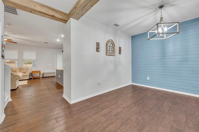 interior space with beamed ceiling, hardwood / wood-style floors, ceiling fan with notable chandelier, and wood walls