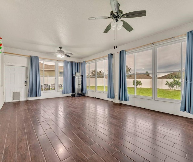 unfurnished living room with a textured ceiling, ceiling fan, and dark hardwood / wood-style flooring