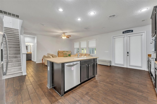 kitchen featuring a textured ceiling, dishwasher, dark hardwood / wood-style floors, and a kitchen island with sink